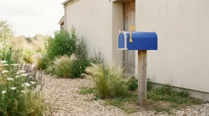 Briefkasten mit hochgestellter Fahne an einer schlichten Hauswand